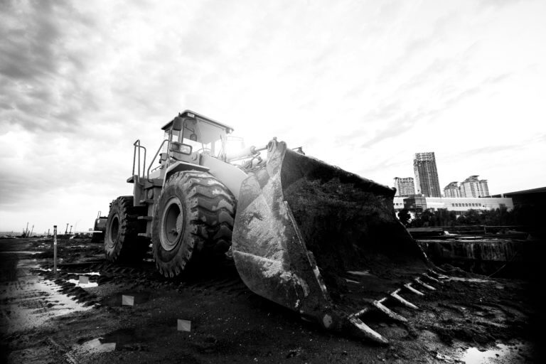 A dig site outside a city featuring an excavator, marking flags, and a TriView