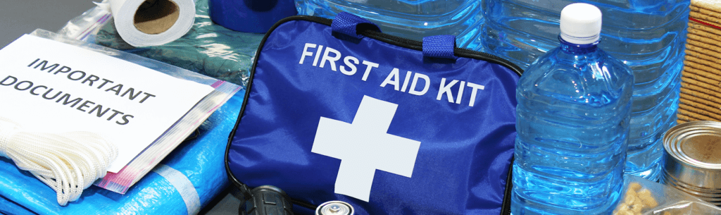 A close-up of a first aid kit, important documents, and water.