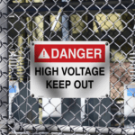 Aluminum High Voltage Warning Sign on a fence